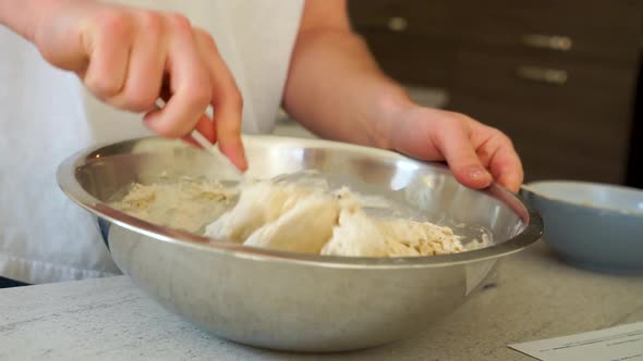 Young Aspiring Chef is Making Pizza Bread Dough to bake, forming the dough in a metal bowl with a me