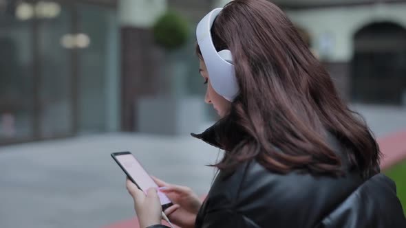 Woman is Chatting in the Smartphone Against the Background of the Evening City