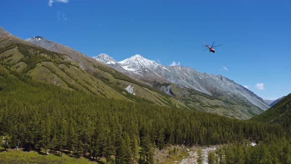 Aerial shot of helicopter flying over trees. Drone Shot .Helicopter low flying in blue sky with gree