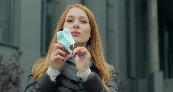 Young Redhead Woman Taking Off Protective Mask Against COVID Virus, Tourist with Medical Mask