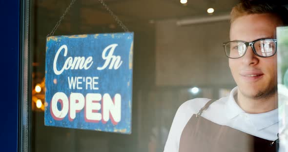 Restaurant opening, waiter owner changes the door plate from Closed to Open, looking for clients