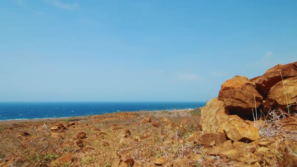 Rugged boulders on Curacao north coast desert with blue Caribbean Sea background