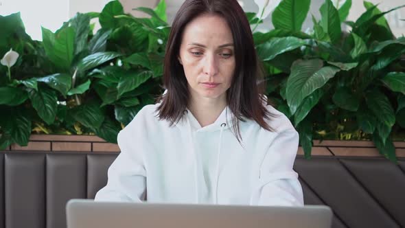 Portrait of a Young Caucasian Female Freelancer Using a Laptop to Work at a Distance Sitting in a
