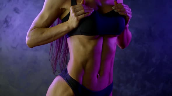 Professional Athlete Girl with Muscular Body and Silicone Breasts Posing in Neon Light Dressed in