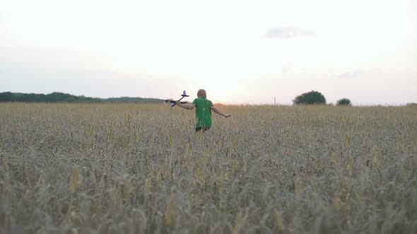 A Boy with an Airplane in His Hands Runs in the Park