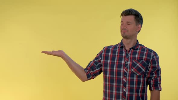 Handsome Man Presenting Something on Empty Hand with Yellow Background