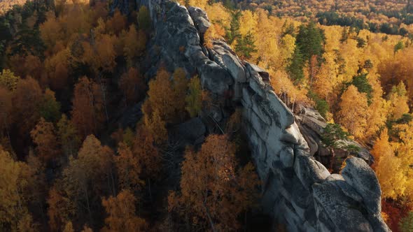 Aerial View of a Cliff Surrounded By a Colorful Autumn Forest at Sunset