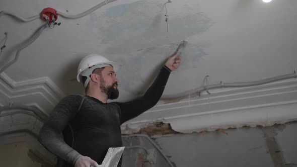 Fat Bearded Adult Man in Protective Helmet and Black Tight Fitting Clothing Remove Construction