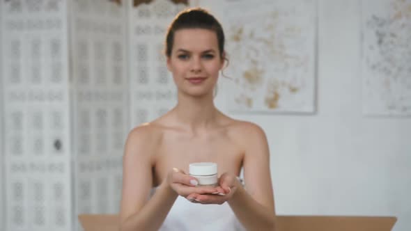 Handsome Cute Woman Stretching Out Jar with Cream to the Camera