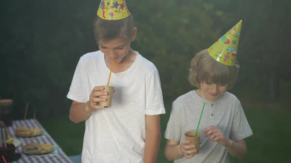 Happy Teenage and Little Brothers Drinking Juice From Paper Cup Laughing Dancing in Slow Motion in