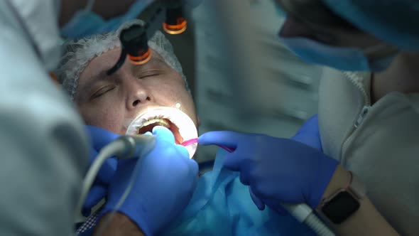 Headshot of Caucasian Man with Mouth Retractor Opening Eyes As Dentist Leaving with Drill and