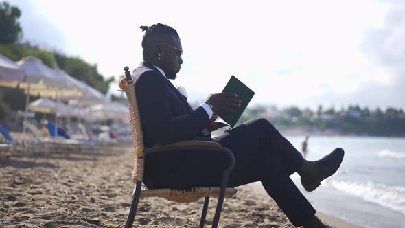 Side View of Serious Handsome Elegant African American Businessman Closing Sketchpad Thinking