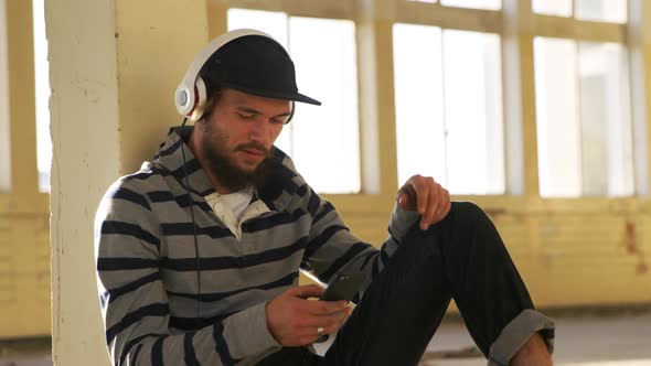 Young man listening to music in empty warehouse