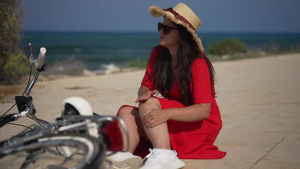 Sad Young Caucasian Woman Rubbing Knee Fell From Bicycle Outdoors on Sunny Summer Day