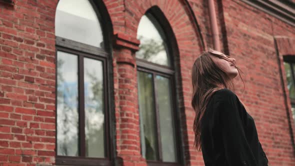 A Young Girl is Posing Against the Backdrop of a Brick Building