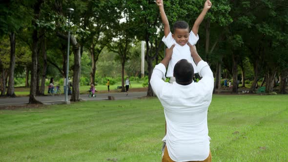 Happy African father and son playing together at public park.