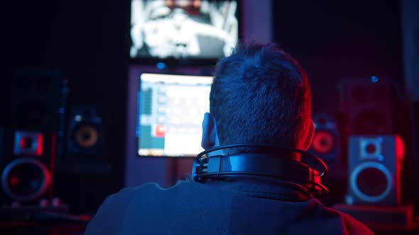 A Man Sound Engineer in Headphones Working in the Studio - Recording a Rap Track