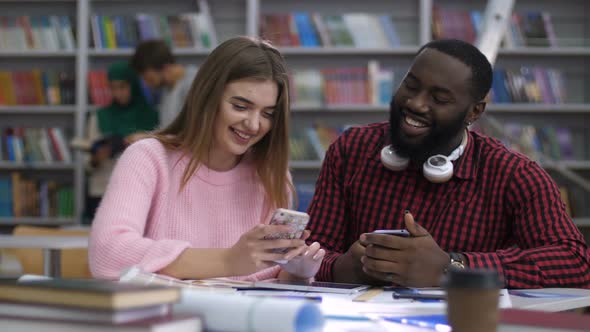 Multi Ethnic Couple Browsing Cellphone in Library