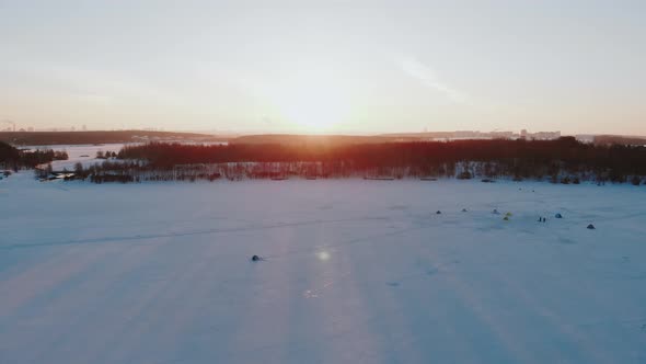 Beautiful Aerial View of Campground on Frozen Lake in Rays of Setting Sun