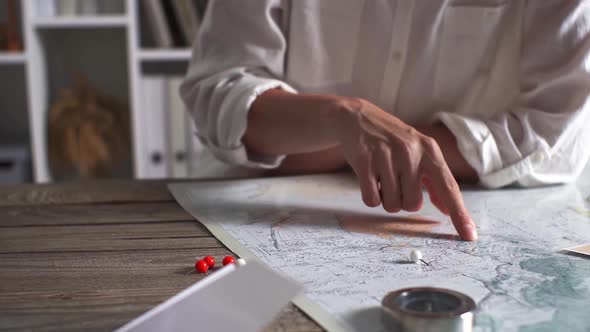 The Hand Of A Young White Girl Tourist Traveler Chooses A Point On The World Map Where He Would