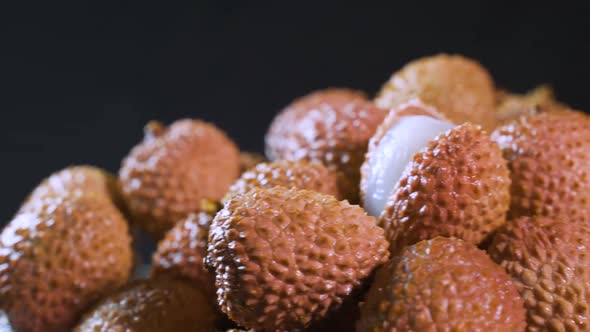 The Girl's Hand Takes Ripe Juicy Lychee Fruits on a Black Background