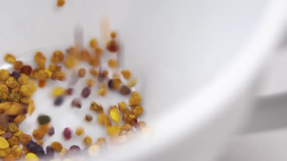 Healthy bee pollen grain falling into a white teacup in slow motion. Macro