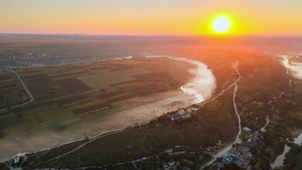 Aerial drone view of the Old Orhei at sunset. Valley with river and fog, village, monastery located 