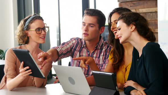 Business executives using laptop mobile phone and digital tablet in meeting