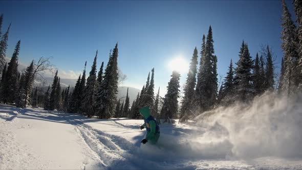 Young female snowboarder riding fresh powder snow in beautiful snowy mountain in sunny winter.