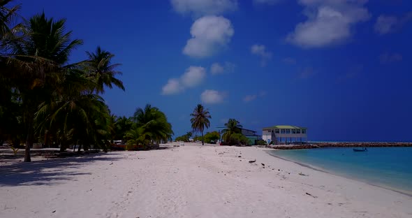 Wide fly over island view of a sunshine white sandy paradise beach and blue water background in colo