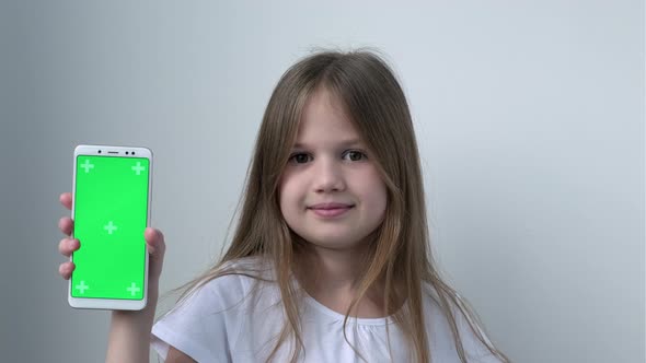 Cute Child Girl Shows Phone with Green Screen Mock Up Cellphone Mobile Telephone