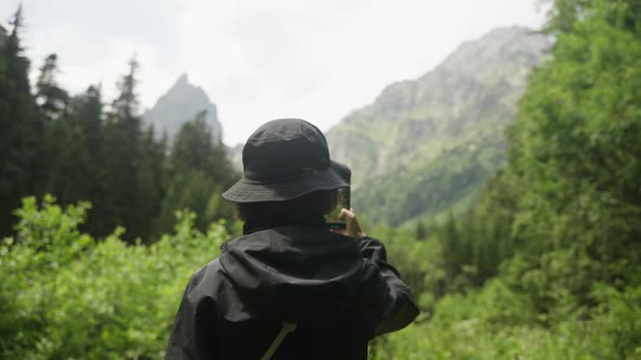 A Happy Tourist Woman Traveling and Take Photo a Smart Mobile Phone Technology Device in Forest