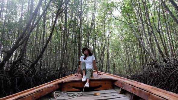 A beautiful young asian woman sitting on a long tail boat while traveling the mangrove forest