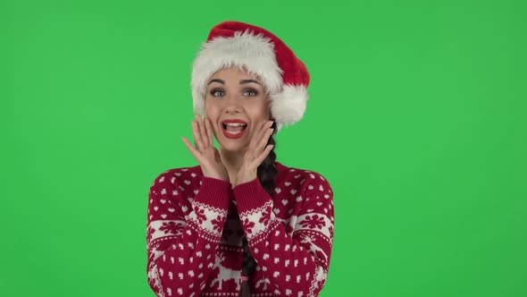 Portrait of Sweety Girl in Santa Claus Hat Is Screaming Calling Someone. Green Screen