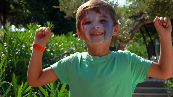 Boy is Jumping Cheerfully with Makeup Painted in the Colors of a French Flag