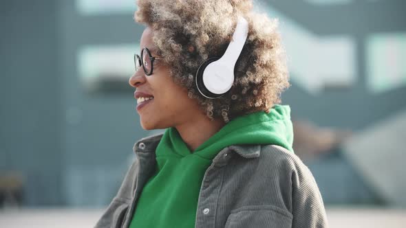 Handsome adult African woman wearing casual clothes dancing and listening music in headphones