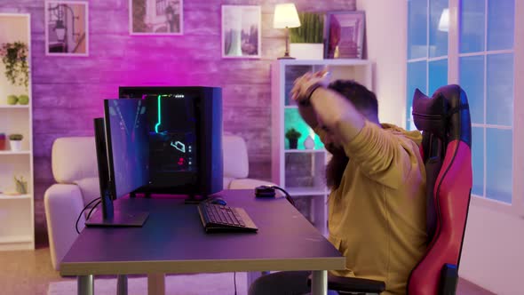 Bearded Man Sitting on Gaming Chair Stretching While Playing Video Games