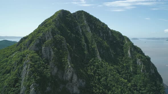 Aerial View of the Tall Mountain Covered By the Forest Towering Over the Empty Valley and Sea on