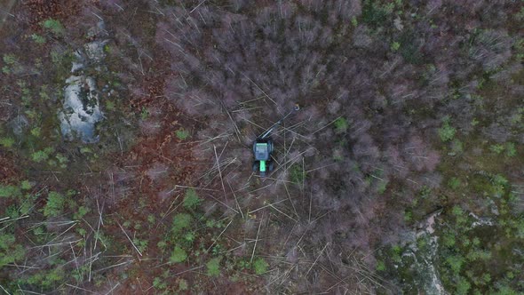 aerial view of green tractor cutting trees in forest