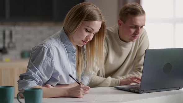 Serious Young Couple Holding Papers Pay Domestic Bills Online on Laptop Checking Bank Account