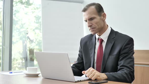 Pensive Businessman Thinking and Working on Laptop