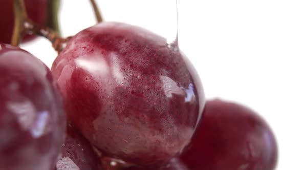 A bunch of red grapes close-up with a splash of water in slow motion on a white background