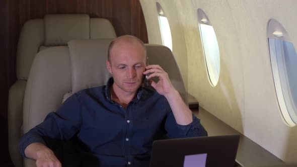 Portrait of investor expert analyst man working on laptop in the plane Talking on the Phone