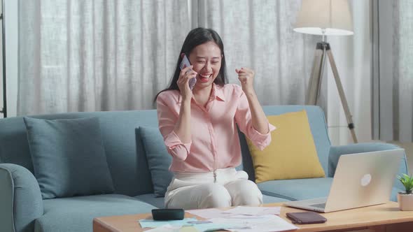 Asian Woman With A Laptop Answering The Call Then Being Happy While Looking At The Bill In Hand