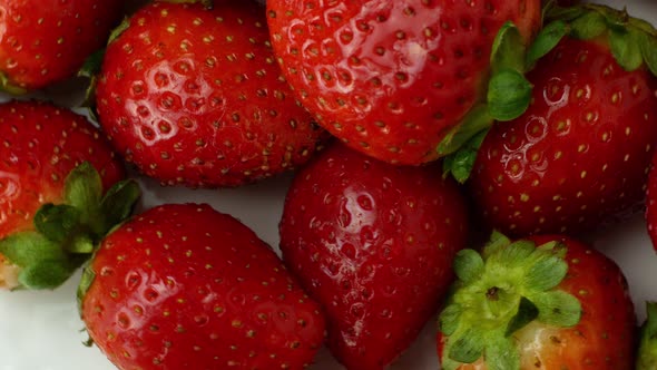 Beautiful ripe red strawberry rotates on a plate. Slow rotation of strawberries close-up top view