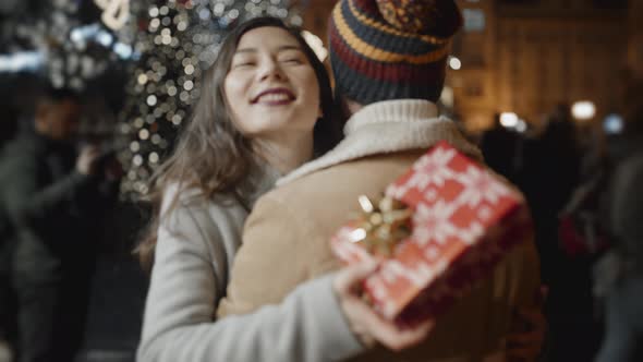 Man Standing Back to Camera Presents a Xmas Gift to Her Girlfriend and She Doesn't Like It