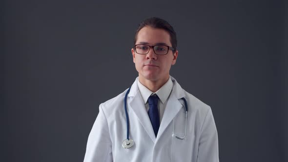 Studio portrait of young professional medical doctor standing over grey background