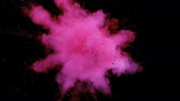 Colorful powder/particles fly after being exploded against black background. Slow Motion.