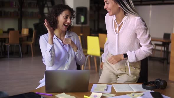 Portrait of Joyful Female Students Studying at Library with Laptop