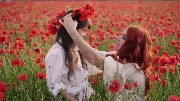 Young Mother Puts Wreath of Poppy Flowers on Her Daughter's Head Close Up